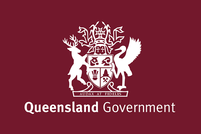 The Queensland Government coat of arms in white on a maroon background — a stag and a brolga flanking a shield above the motto Audax at Fidelis