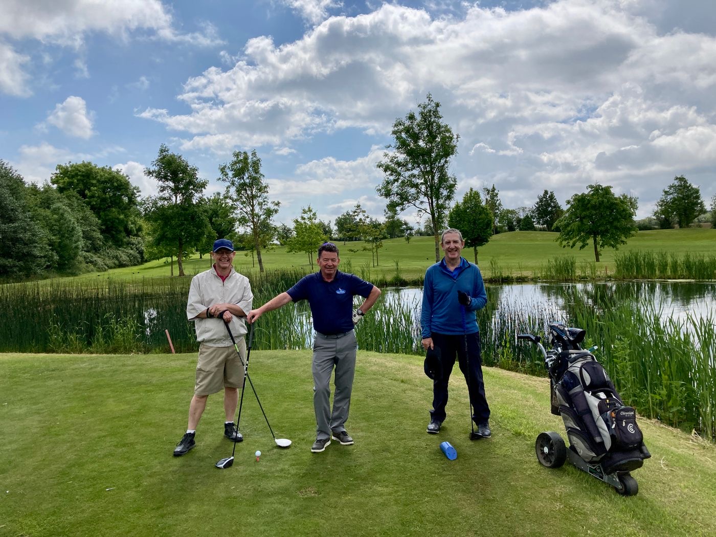 Three friends smiling on the tee at a charity golf day